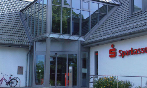 Umbau eines 50er Jahre Walmdach-Winkelbungalows mit 70er Jahre Flachdachanbau zu einem repräsentativen Sparkassengebäude<br/>
Außenansicht